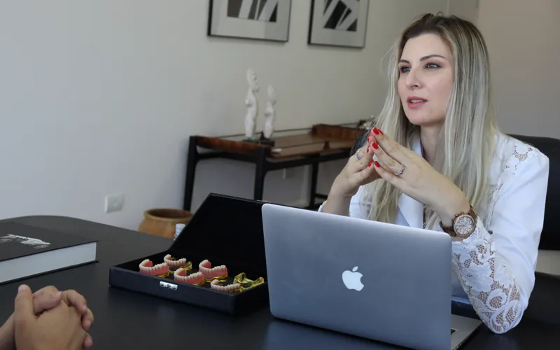 Dra. Jéssica com modelos odontológicos e notebook, em análise técnica